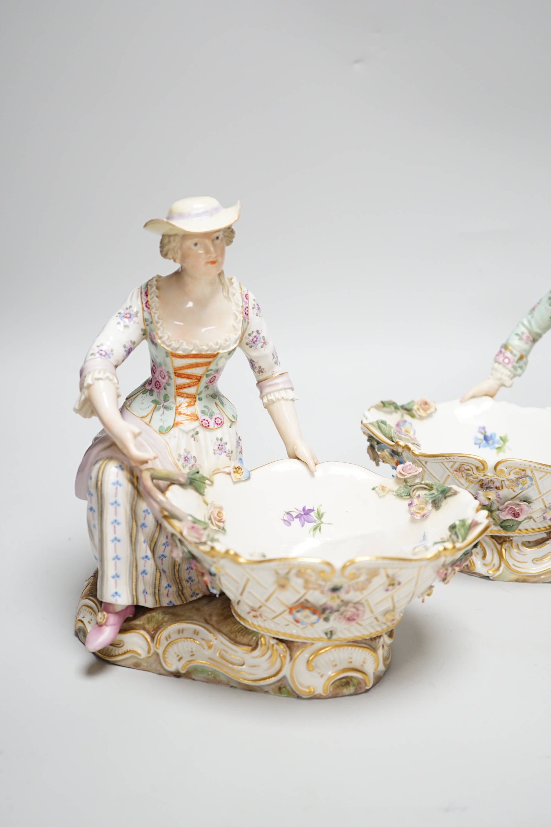 A large pair of Meissen salts in the form of a seated man and a woman in 18th century dress (a.f.), 21cm high
